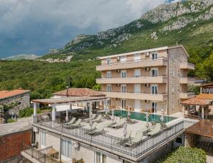 a hotel with a balcony with chairs and a swimming pool at Apartments Đurašević in Sveti Stefan