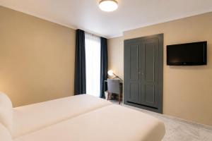 a bedroom with a bed and a flat screen tv at Petit Palace Puerta de Triana in Seville