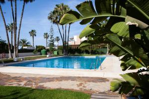 a swimming pool with palm trees and a building at Casa Mari Pepa beach & pool in Benajarafe