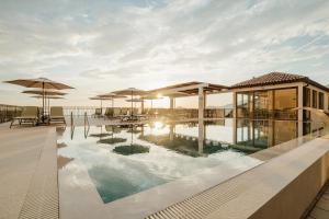 a pool with tables and umbrellas on a building at Apartments Đurašević in Sveti Stefan