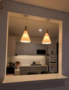 a kitchen with two lights and a counter with chairs at RR Travertine House Cikarang in Jatirarangan