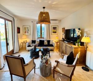 a living room with a couch and a tv at La Villa Bohème Piscine Jardin Vue Luberon in Oppède