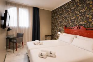 a hotel room with two beds and a chair at Petit Palace Puerta de Triana in Seville +57 photos