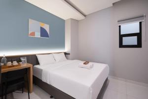 a bedroom with a white bed and a desk at Cove Vaia in Bandung