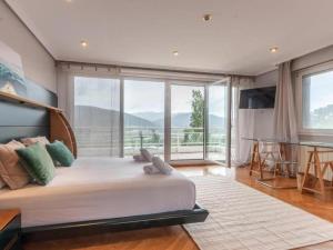 a bedroom with a large bed with a large window at VILLA ISLAS Urdaibai in Isla Becoa +38 photos