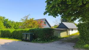 a house with a hedge and a trash can next to a street at Lilla lugnet in Ystad