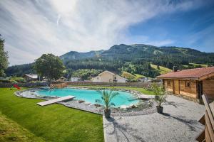 a swimming pool in a yard with a house and mountains at Almhütte Eibingalm in Saalbach-Hinterglemm