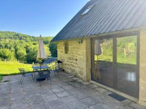 a patio with a table and chairs and sliding glass doors at Le Gîte de Couturas in Saint-Hilaire-les-Courbes
