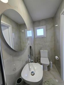 a bathroom with a sink and a toilet and a mirror at Morera Suite Paliouri in Paliouri