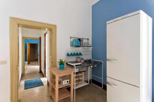 eine Küche mit blauen Wänden, einem Tisch und einem Kühlschrank in der Unterkunft Moon Light Hostel in Palermo