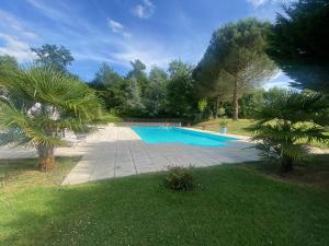 a swimming pool in a yard with palm trees at Gîte des Petites Fadettes "MELUSINE" in Lannepax