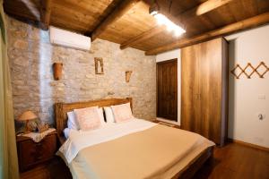 a bedroom with a bed and a stone wall at Villa Shuaipaj in Gjirokastër