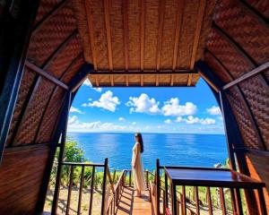 a woman standing on a balcony looking out at the ocean at Sea Cliff Eco Nusa Penida in Polilit