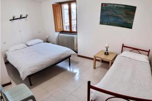 a bedroom with two beds and a table at Ostello del Parco di Monte Cucco in Costacciaro