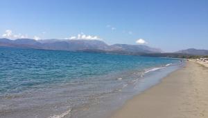a beach with the ocean and mountains in the background at olivensun apartment 7 in Gythio
