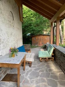 eine Terrasse mit zwei Bänken, einem Tisch und Stühlen in der Unterkunft Chalet Angelo in Ponte di Legno