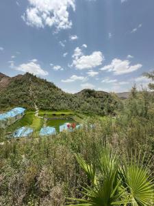 a pond in a field with mountains in the background at منتجع خيال رفيف in Ḩarshaf
