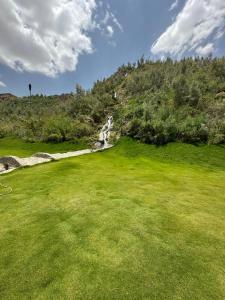 a golf course with a green field and a waterfall at منتجع خيال رفيف in Ḩarshaf +3 photos