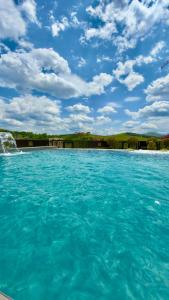 a pool of blue water with a blue sky and clouds at Apartman Romanija Wellness & Spa in Potoci