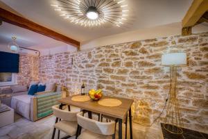 a dining room with a stone wall and a table and chairs at Olive & Wave Cottage in Karousádes