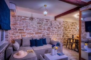 a living room with a couch and a brick wall at Olive & Wave Cottage in Karousádes