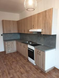 a kitchen with wooden cabinets and a stove and a sink at Ubytování Klicperova in Chlumec nad Cidlinou
