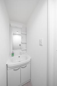 a white bathroom with a sink and a mirror at Astage Chitose Suehiro 103 in Chitose