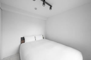 a bedroom with a white bed and a lamp at Astage Chitose Suehiro 103 in Chitose