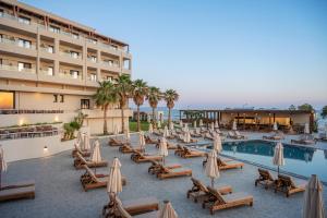 a hotel with a pool with chairs and umbrellas at Oya Beach Resort in Hersonissos