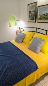 a bed with yellow and blue sheets and pillows at Apartment Neno - Terrace & Parking in Veli Lošinj