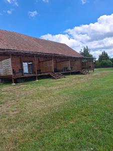 a large wooden building with chairs in a field at J&L Lake Resort in Grądzkie
