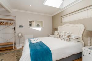a bedroom with a white bed with a blue blanket on it at Fig Tree Cottage - Leafy Constantia Cottages in Cape Town +40 photos