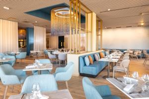 a restaurant with tables and chairs and a chandelier at Parkest Hôtel & Spa in Genas