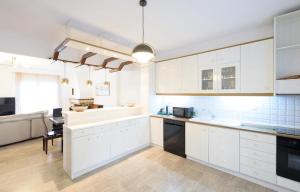 a large kitchen with white cabinets and a table at Cleopatra Residence in Perea +6 photos