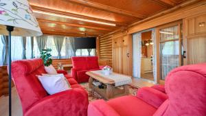 a living room with red chairs and a table at Villa Pine Log by Villas Guide in Dubrovčan