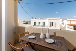 a wooden table with plates and vases on a balcony at Vivlos Stays - Ageri in Vívlos