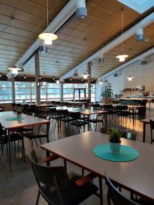 an empty cafeteria with tables and chairs and windows at Tanhuvaaran urheiluopisto & Sport Resort in Savonlinna