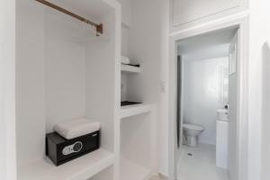 a white bathroom with a toilet and a black speaker at Vivlos Stays - Ageri in Vívlos +37 photos