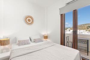 a white bedroom with a bed and a balcony at Vivlos Stays - Ageri in Vívlos
