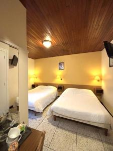 a bedroom with two beds and a wooden ceiling at Les Loges du Vercors in Vizille