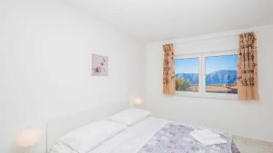 a white bedroom with a bed and a window at Villa Isabella by Villas Guide in Malinska +22 photos