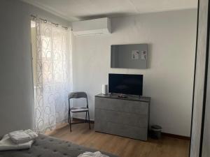 ein Schlafzimmer mit einem Fernseher und einem Stuhl in einem Zimmer in der Unterkunft DammHouse in Campobasso