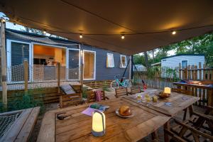 a patio with a wooden table and a house at Flower Camping Au Bois des Biches in Saint-Hilaire-de-Riez
