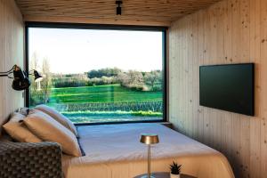 a bedroom with a large window and a tv at Vineyard Cabins at Château Puynard in Berson