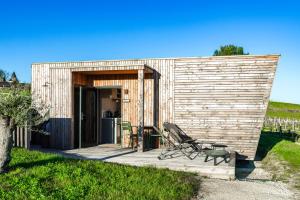 a wooden building with a chair on a deck at Vineyard Cabins at Château Puynard in Berson