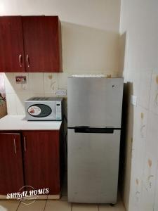 a kitchen with a white refrigerator and a microwave at Shikaz Homes 2 Bedroom Near Jkia Airport in Nairobi