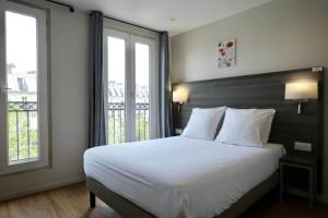 a bedroom with a large white bed with two windows at Hipotel Paris Voltaire Bastille in Paris +78 photos