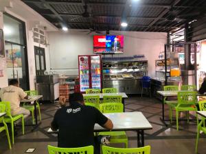 people sitting at tables in a restaurant with green chairs at Hotel Arba in Kuala Lumpur