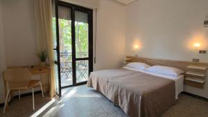 a bedroom with a bed and a desk and a window at Hotel Abay in Rimini