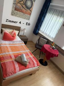 a bedroom with a bed with a red blanket and a table at Hotel Garni in Burghausen +26 photos